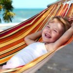 Lachendes Kind am Strand in einer Hängematte